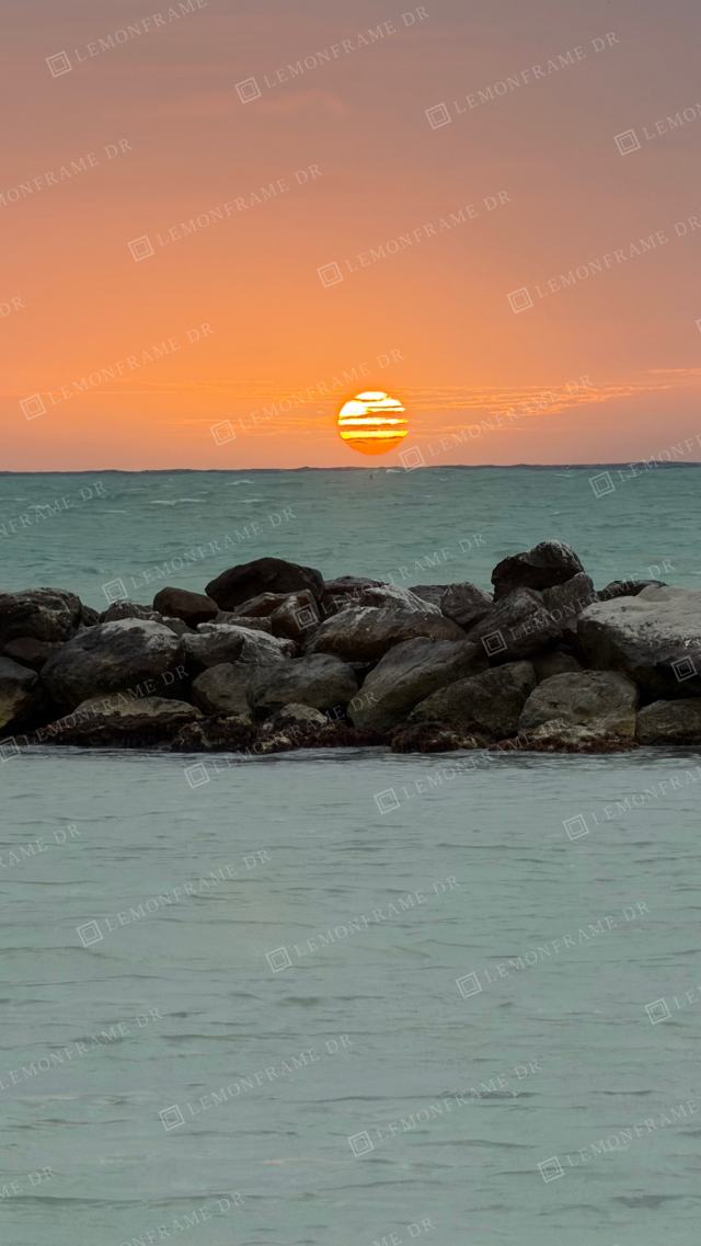 Sol rayado sobre el mar turquesa y las rocas