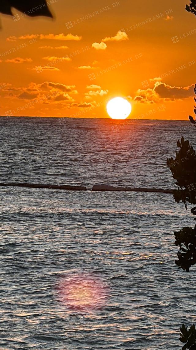 Sol pleno sobre el mar entre nubes naranjas